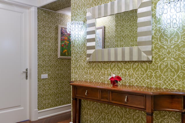 A hallway with patterned green wallpaper.