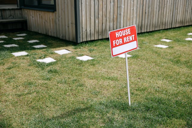 A “for rent” sign in a yard.